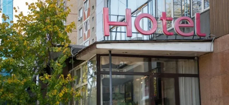 Panoramic view of Almaty city skyline with mountains and budget hotel entrance in foreground