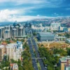 Aerial view of Almaty city with snow-capped Trans-Ili Alatau mountains, popular destination for car rental tourism