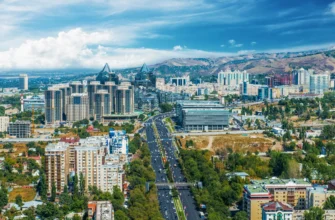 Aerial view of Almaty city with snow-capped Trans-Ili Alatau mountains, popular destination for car rental tourism