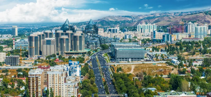 Aerial view of Almaty city with snow-capped Trans-Ili Alatau mountains, popular destination for car rental tourism