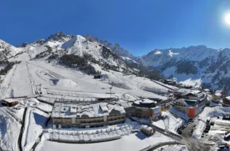 Aerial view of Shymbulak Mountain Resort with snow-covered slopes and Almaty city in background