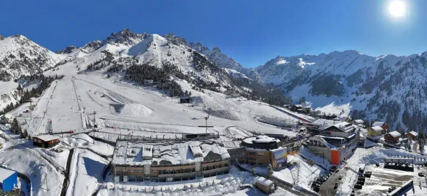 Aerial view of Shymbulak Mountain Resort with snow-covered slopes and Almaty city in background