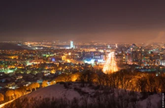 Almaty cityscape at night with illuminated Tian Shan mountains in background reflecting nightlife scene