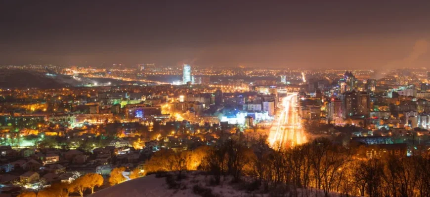 Almaty cityscape at night with illuminated Tian Shan mountains in background reflecting nightlife scene