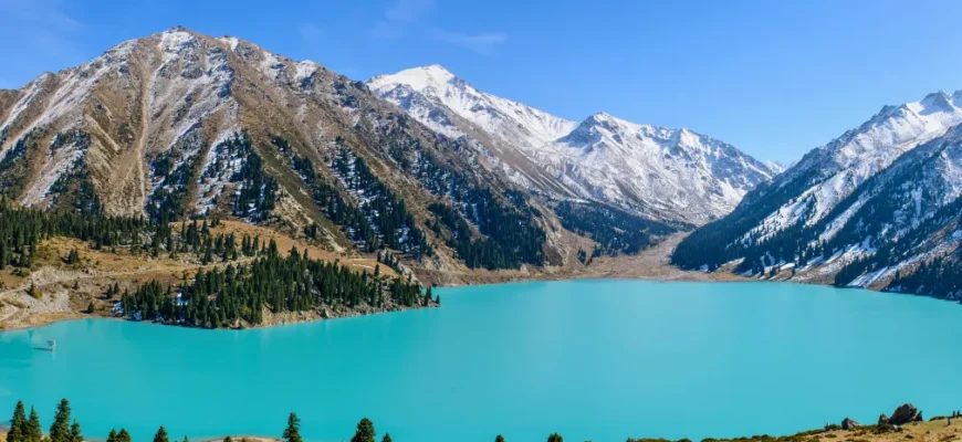 Stunning turquoise waters of Big Almaty Lake surrounded by snow-capped Tian Shan mountains peaks at 2511 meters altitude in Kazakhstan
