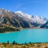 Turquoise Big Almaty Lake with snow-capped Tien Shan peaks in June