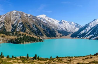 Turquoise Big Almaty Lake with snow-capped Tien Shan peaks in June